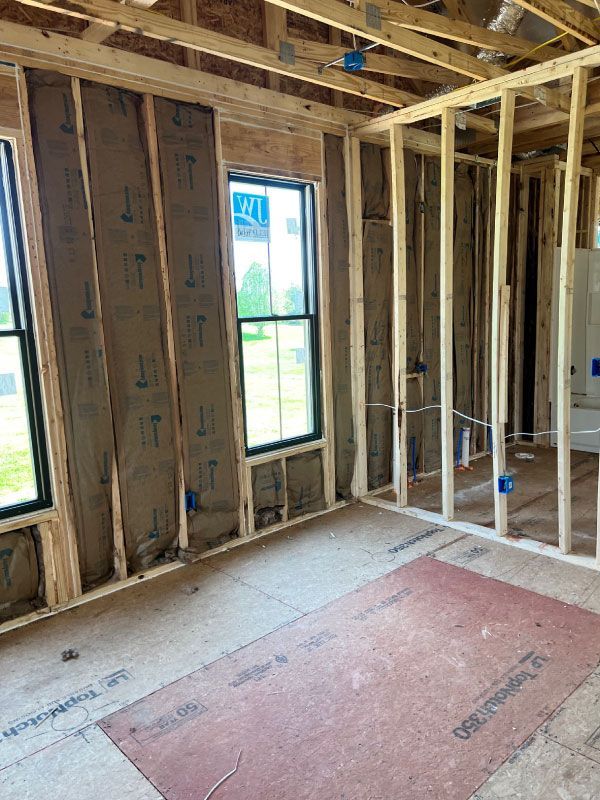 Unfinished room with exposed framing, insulation, and a window under construction.