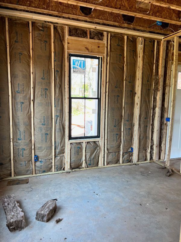 Unfinished room with exposed wall studs, a small window, and concrete floor during construction
