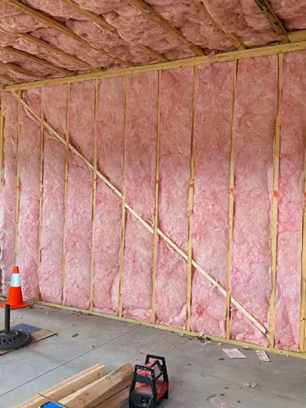 Garage wall insulated with pink fiberglass batt insulation and exposed framing under a sloped ceiling.