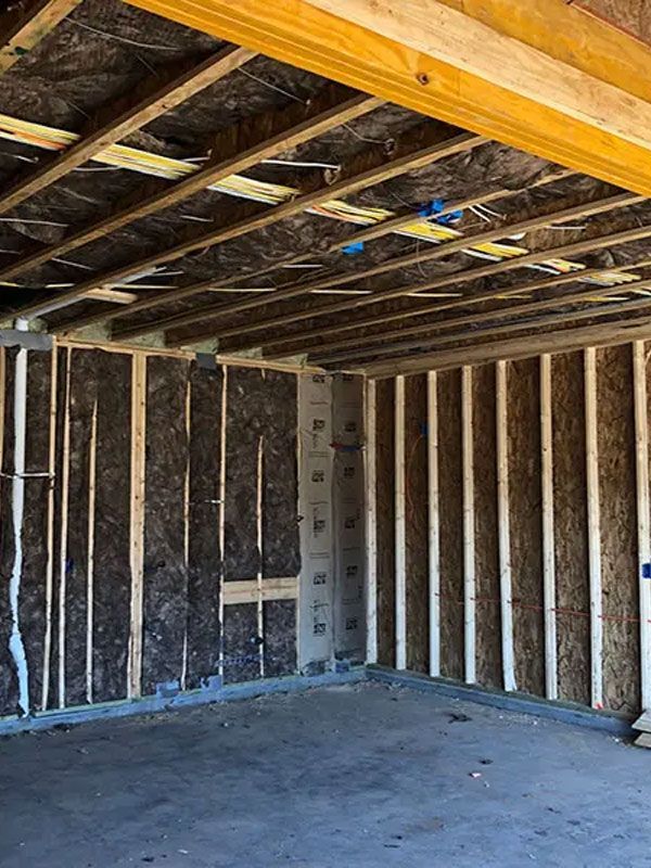Unfinished room with exposed wall studs, insulation, and ceiling joists over a concrete floor.