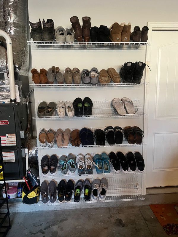 Wire shoe rack filled with assorted shoes and boots in a garage or mudroom