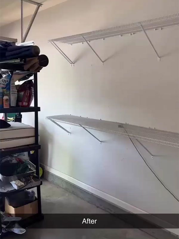 Empty white wall with two newly installed wire shelves above a black storage rack.