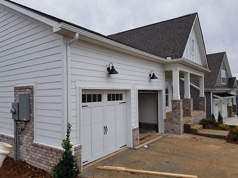White house exterior with garage, stone accents, and a driveway in front