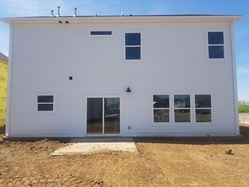 White two-story house exterior with sliding glass door and multiple windows under construction