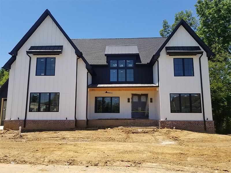 New construction of a two-story white house with black trim and a covered front entry.