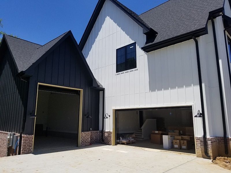 New modern houses with black and white siding and open garage bays in daylight