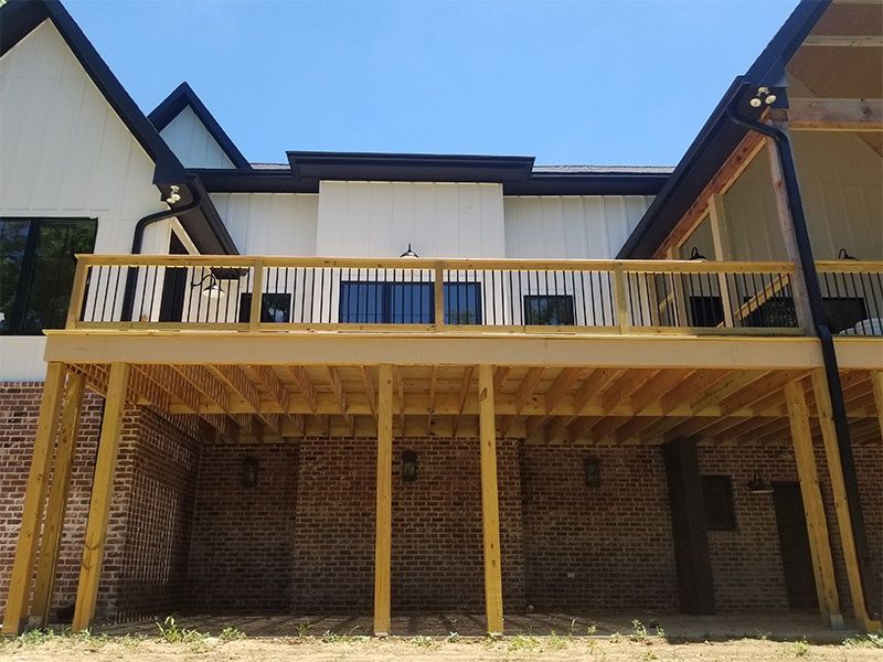 Brick house with a yellow-railed balcony and wooden posts under a blue sky