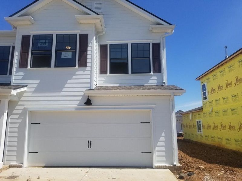 New white two-story house with a garage under construction next to yellow house wrap
