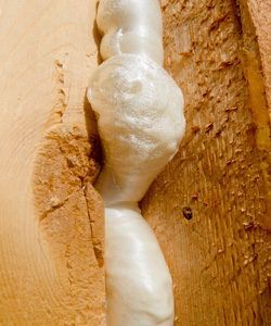 White expanding foam filling a crack between two wooden boards