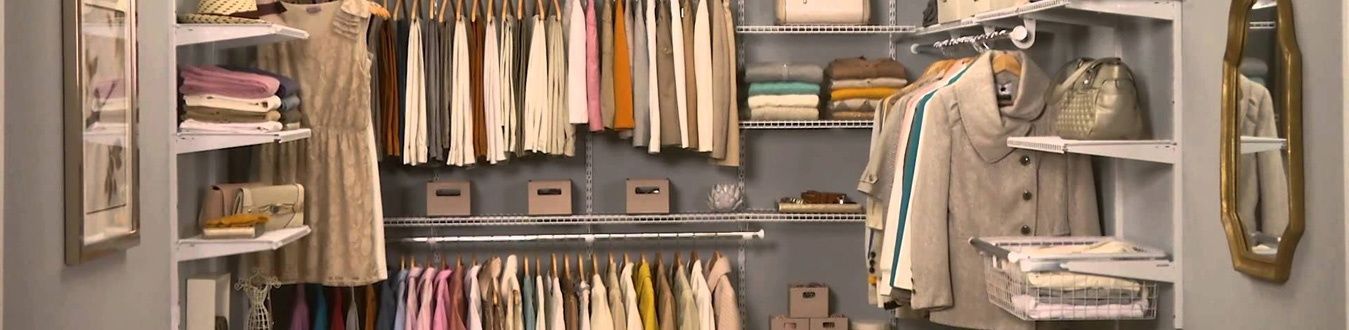 Closet with neatly hung clothes, shelves, and hanging garments in a neutral-toned room