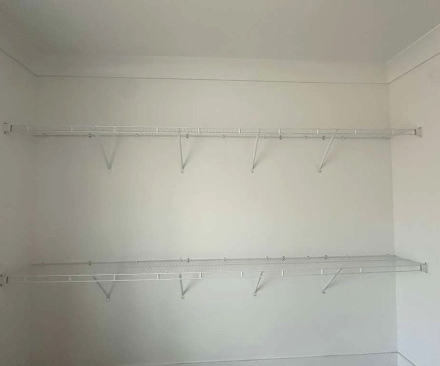 Empty white closet with two wire shelving racks mounted on the wall