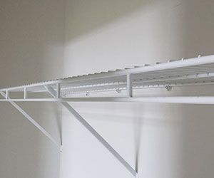 White wire closet shelving mounted on a beige wall with support brackets