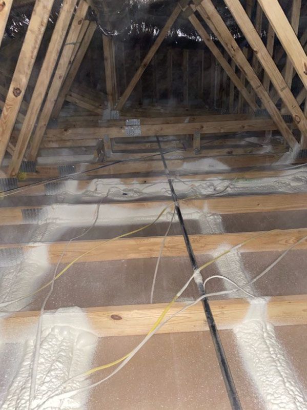 Attic crawlspace with exposed wooden beams and reflective insulation along the floor and walls