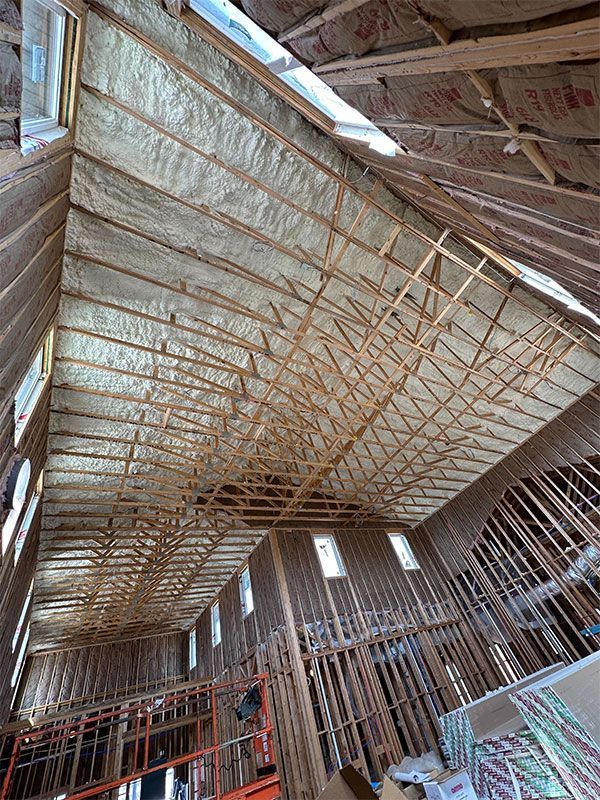 Interior of a barn under construction, showing wooden roof trusses and wall framing