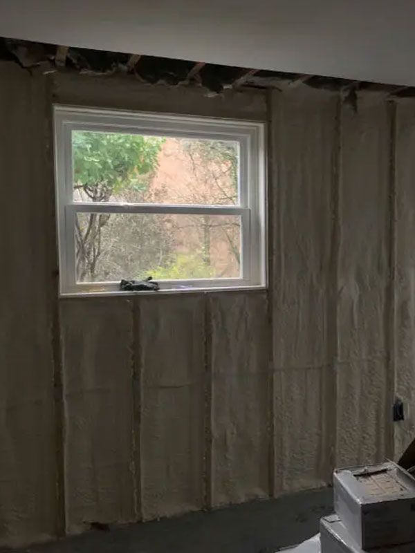 Partially finished room with insulated walls and a window showing trees outside