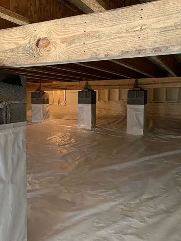 Crawlspace with exposed wooden beams, plastic vapor barrier, and insulated support posts