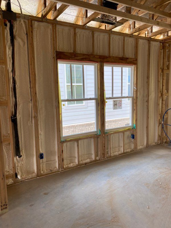 Unfinished room with exposed framing, a double window, and a concrete floor under construction
