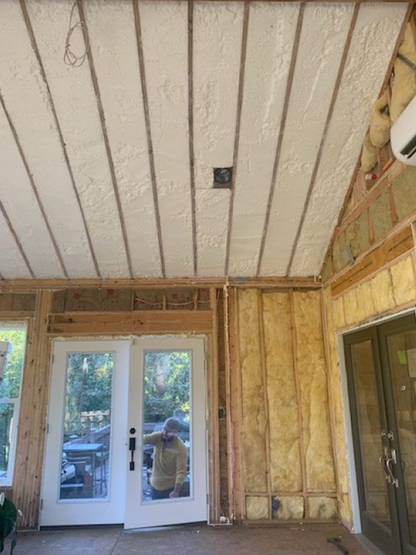 Partially finished room with exposed insulation, white beadboard ceiling, and glass doors to a deck