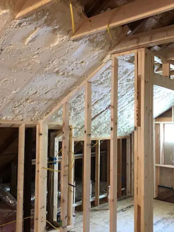 Unfinished attic with exposed wooden framing and spray foam insulation on the sloped roof.