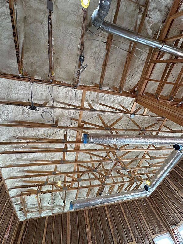Interior ceiling with exposed wood trusses and insulation under construction