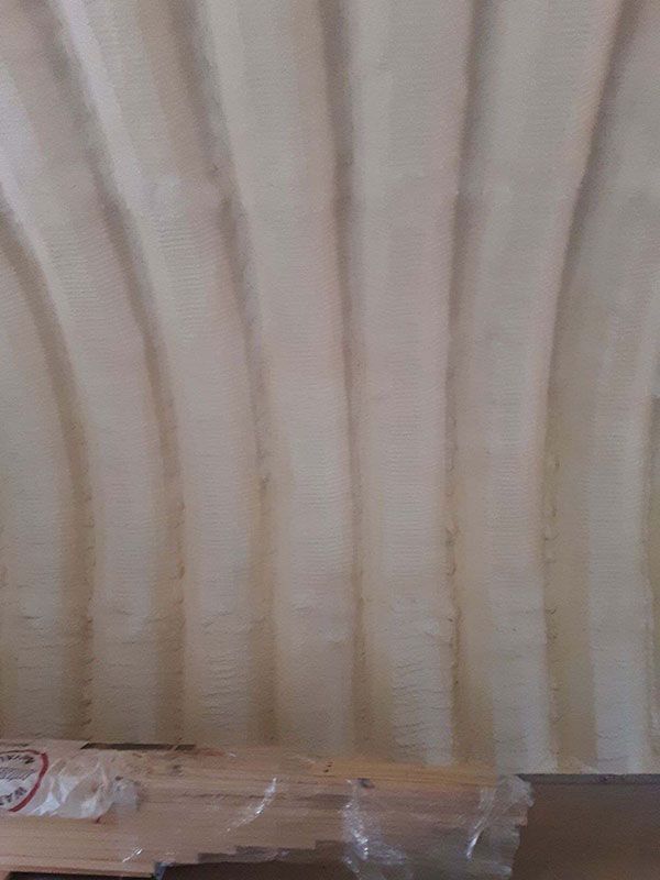 Close-up of a light-colored wavy wall with a wooden beam at the bottom