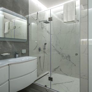 Modern bathroom with glass shower, white marble walls, and curved vanity sink