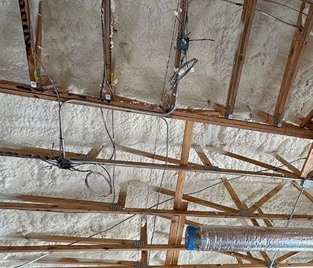 spray-foam Exposed wooden beams with spray foam insulation applied in a ceiling installation