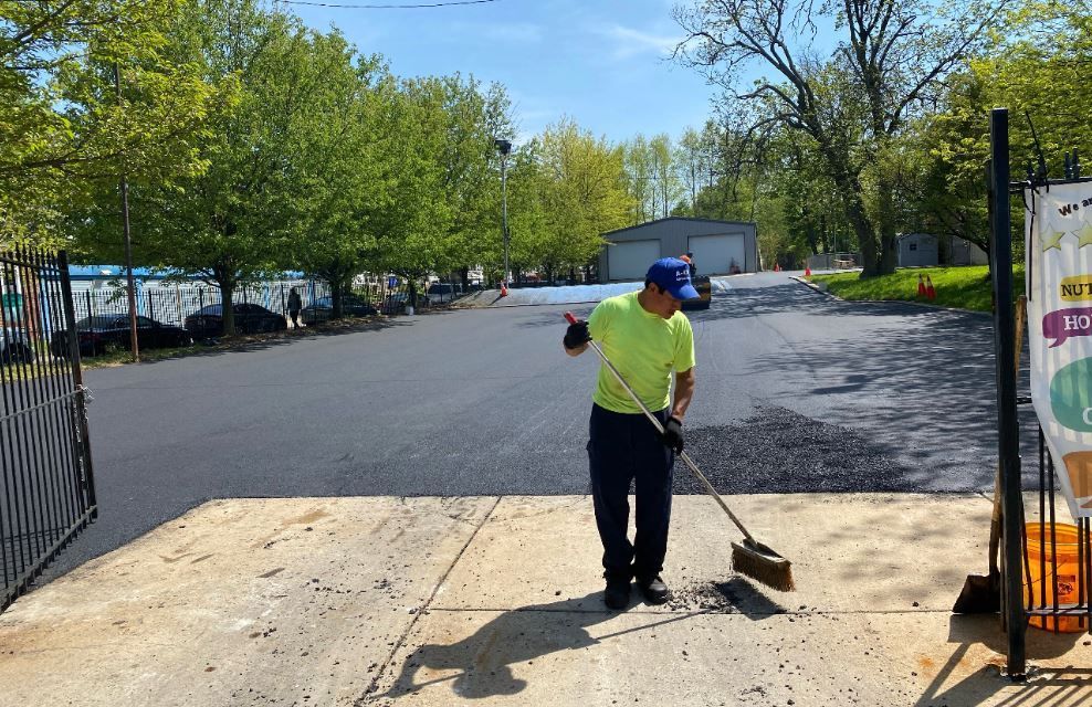 A man is sweeping the sidewalk with a broom.