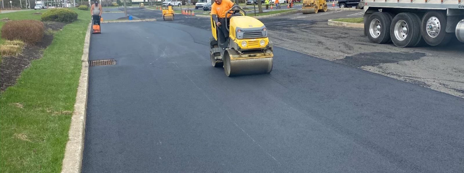 A man is driving a yellow roller on a road.