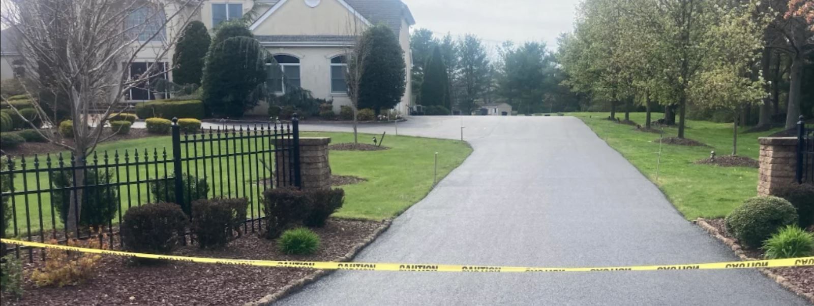 A driveway leading to a large house with a yellow tape covering it.