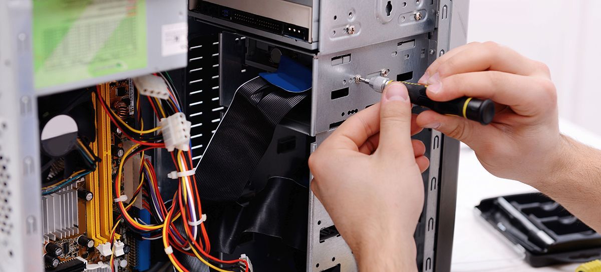 Hands use a screwdriver to attach a component to the metal frame of an open computer tower.