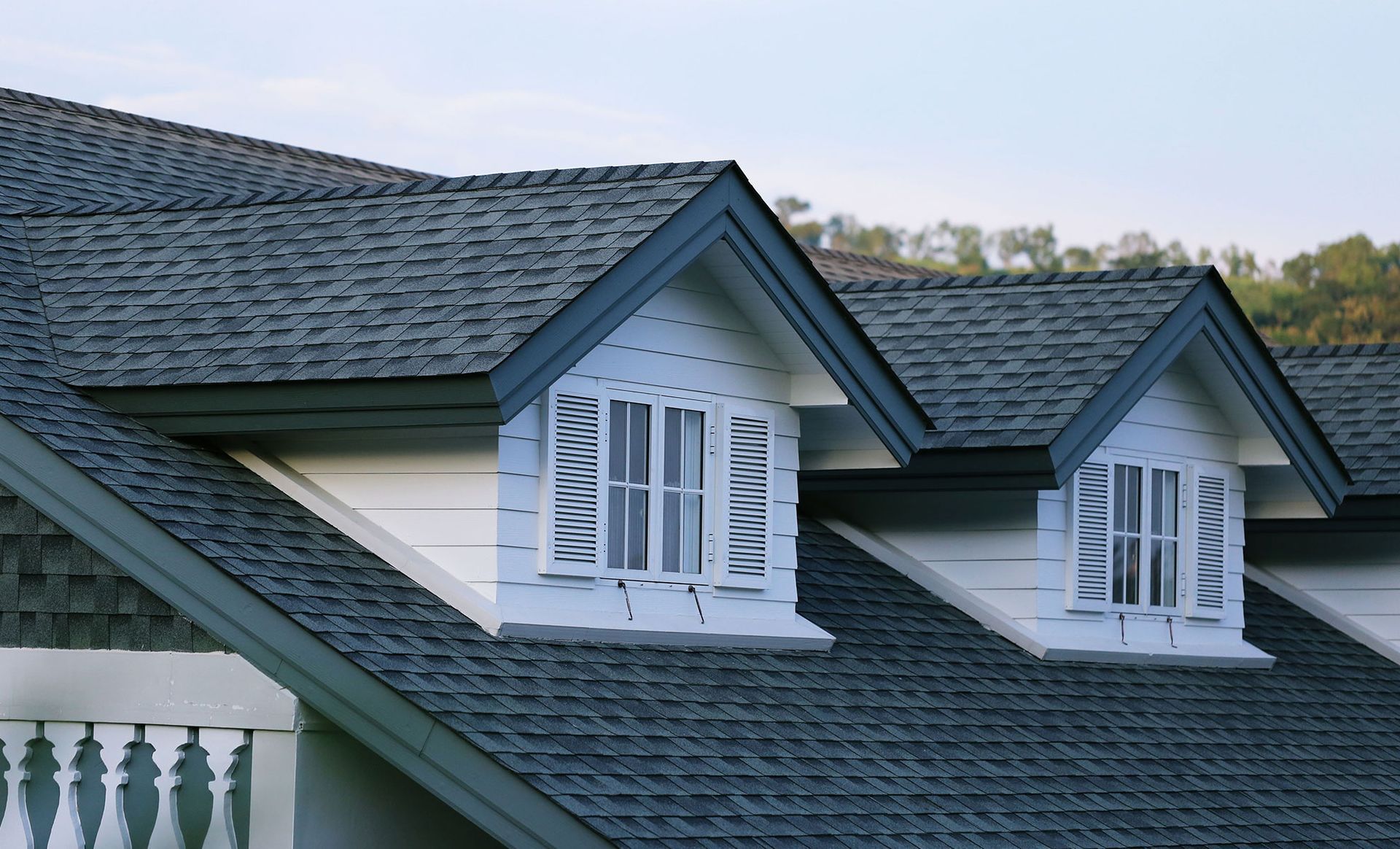Gray asphalt shingle roof with two white dormer windows and dark blue trim.