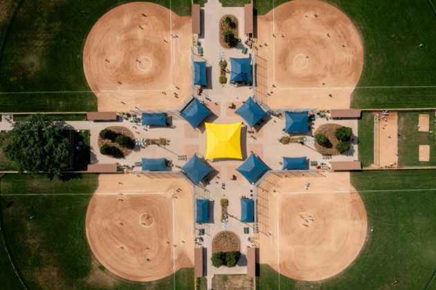 An aerial view of a baseball field with a yellow umbrella in the middle.