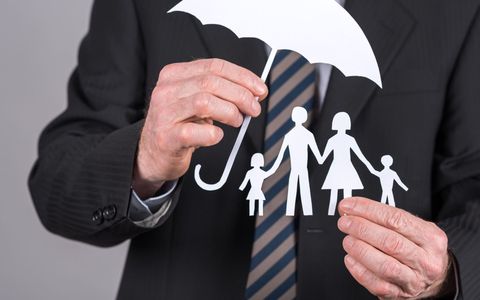 Man holding a cutout of an umbrella protecting a family
