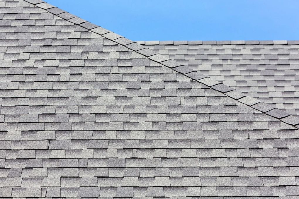 Gray asphalt shingle roof against a clear blue sky.