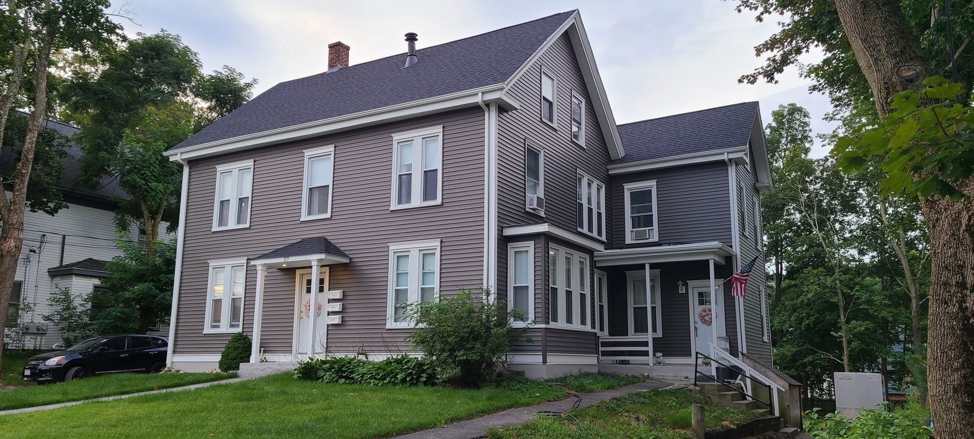 A two-story house with a unique tiger stripe facade, set against a green lawn and trees.