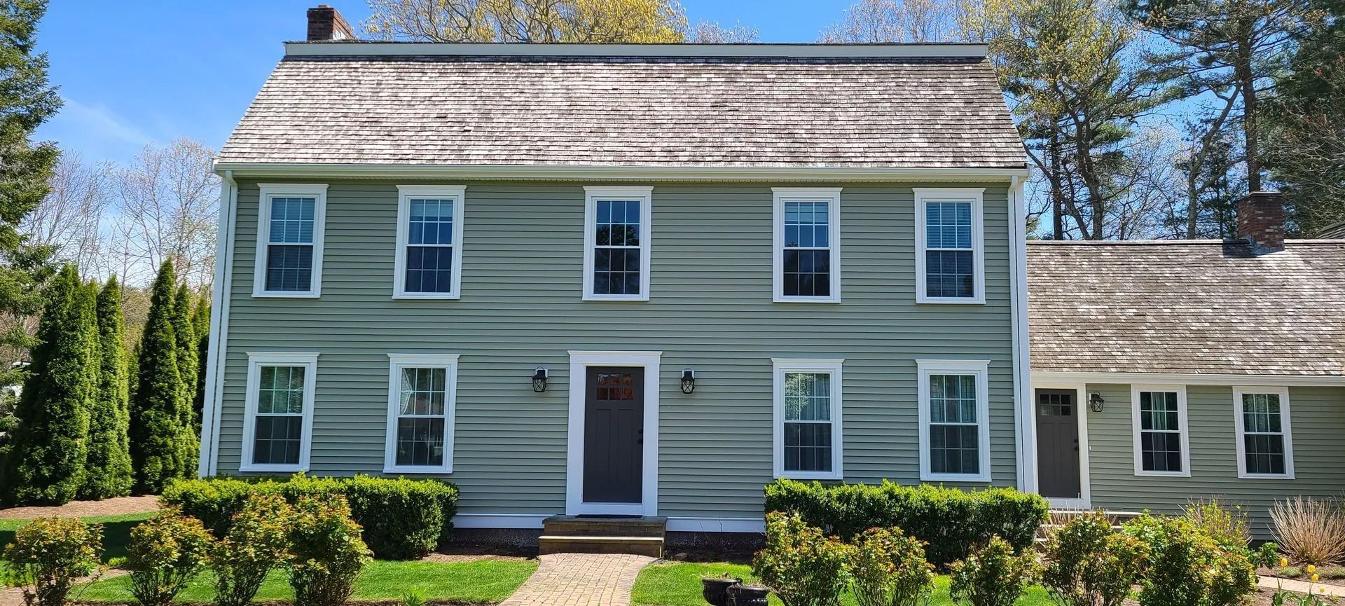 A two-story yellow house with a two-car garage. A car is parked in the garage. Green front door.