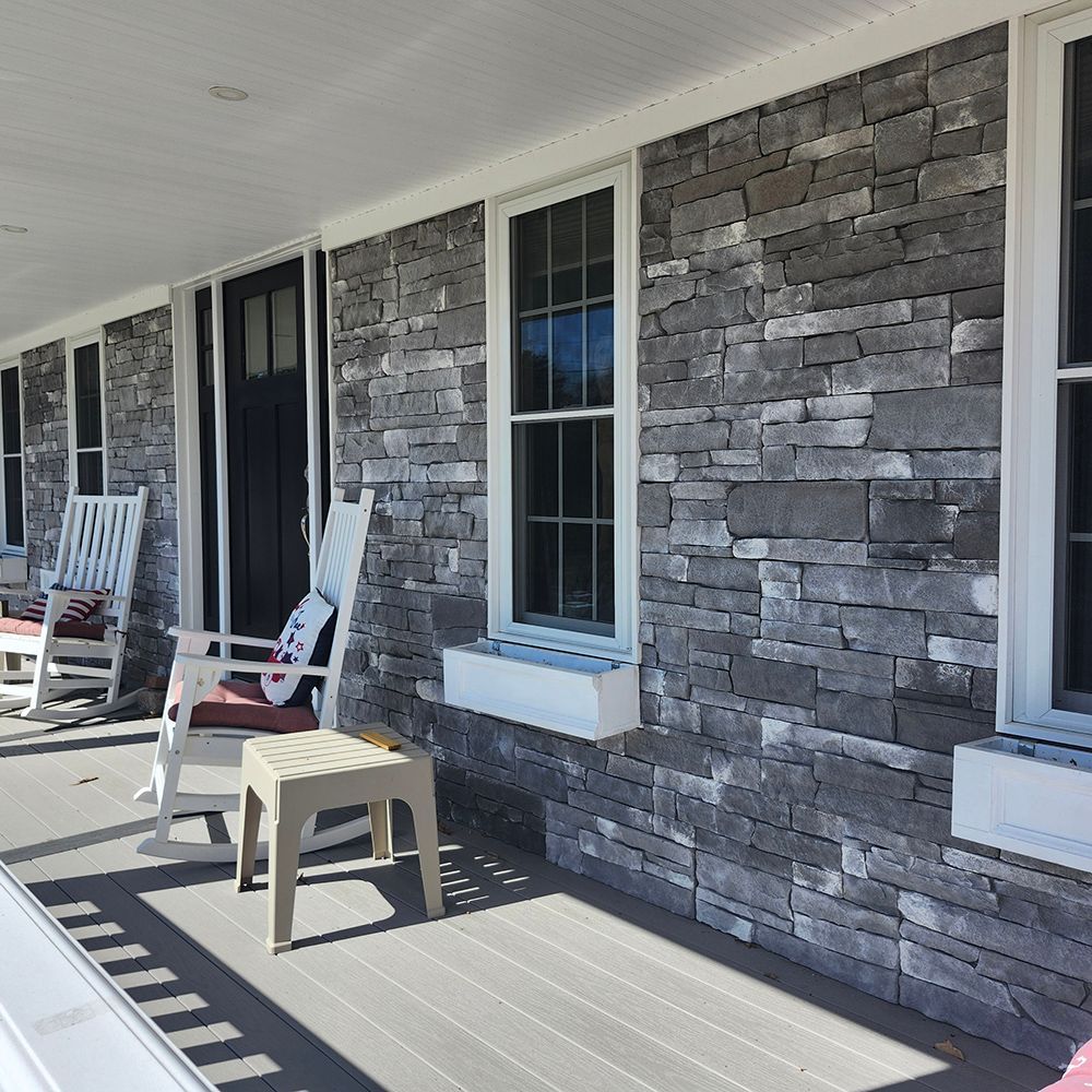 Porch with gray stone facade, white trim, windows, and rocking chairs.
