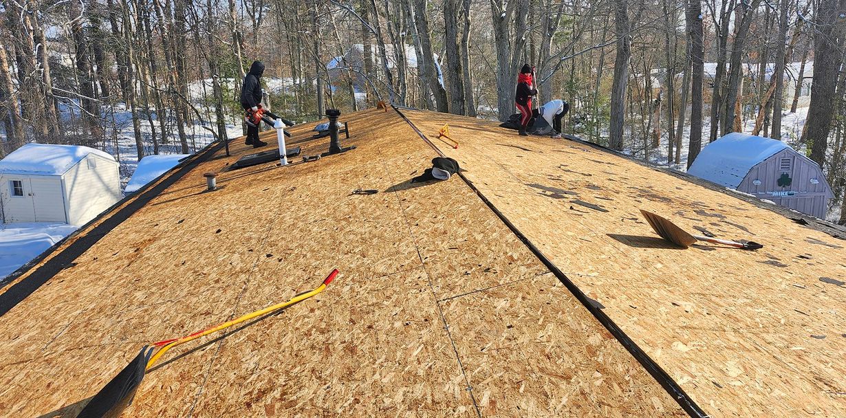 Triangular roof with grey shingles, small windows, and large wooden-framed windows on a white building.