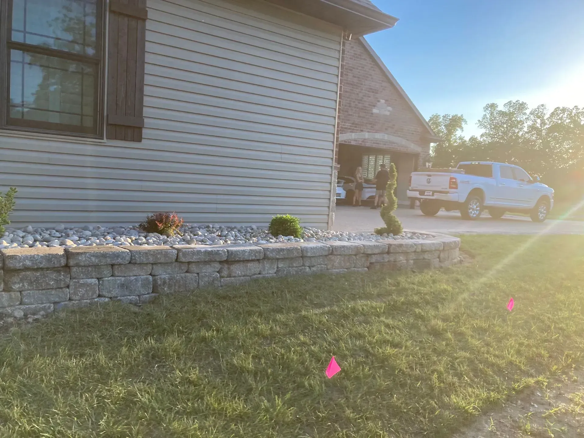 House exterior with stone retaining wall, landscaping, and a white truck in the driveway.