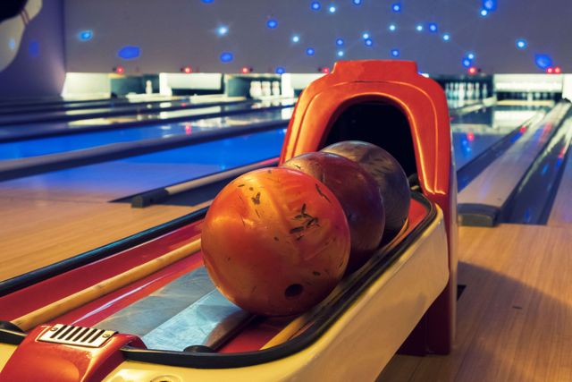 Bowling ball in a lane return at a neon-lit bowling alley, with pins and lanes in the background