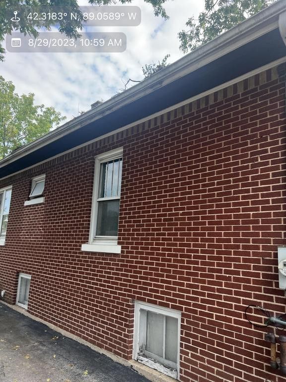 Red brick building with white-framed windows, dark trim, and a cloudy sky.