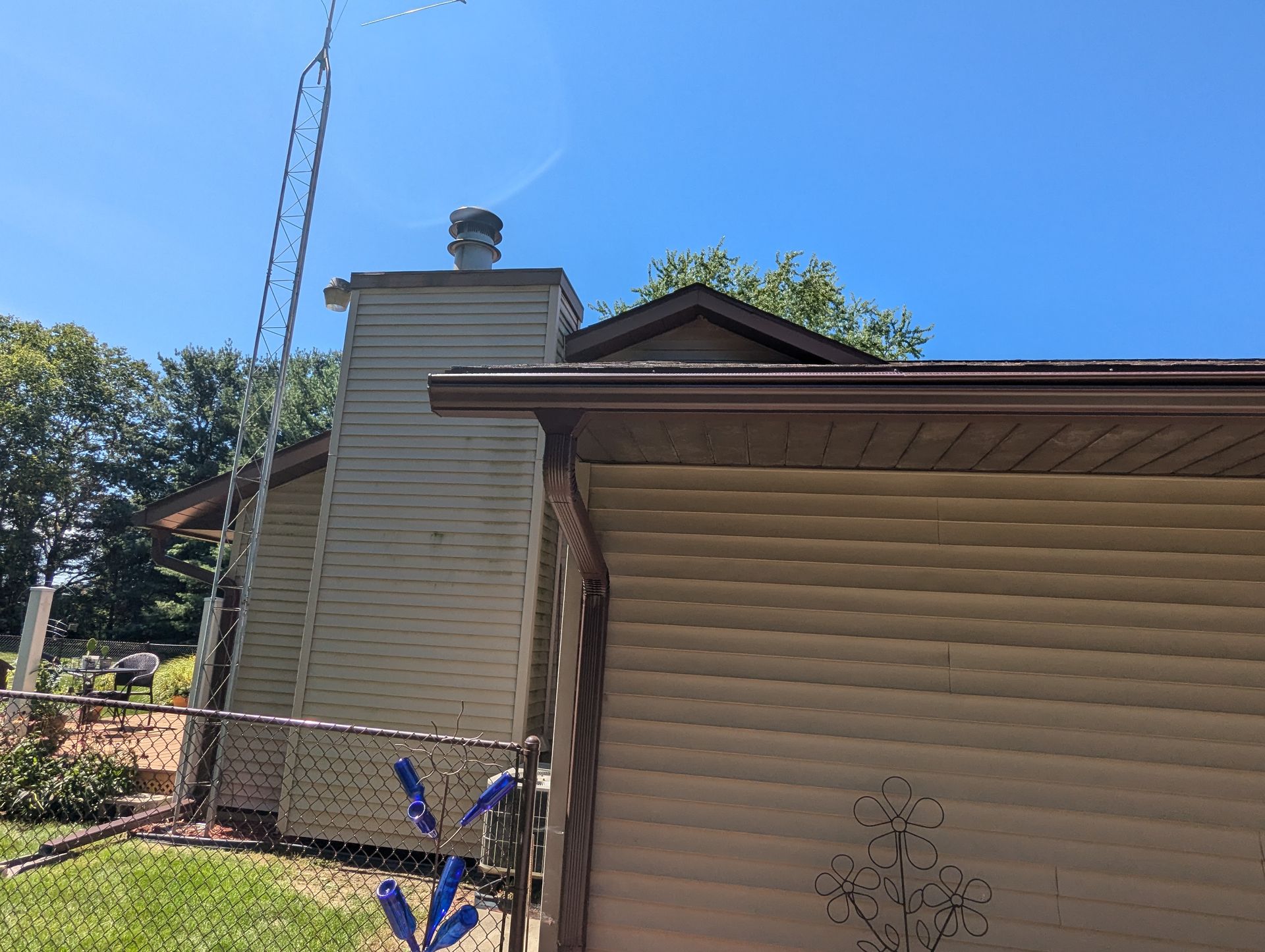 Tan house with chimney, brown trim, and blue sky.