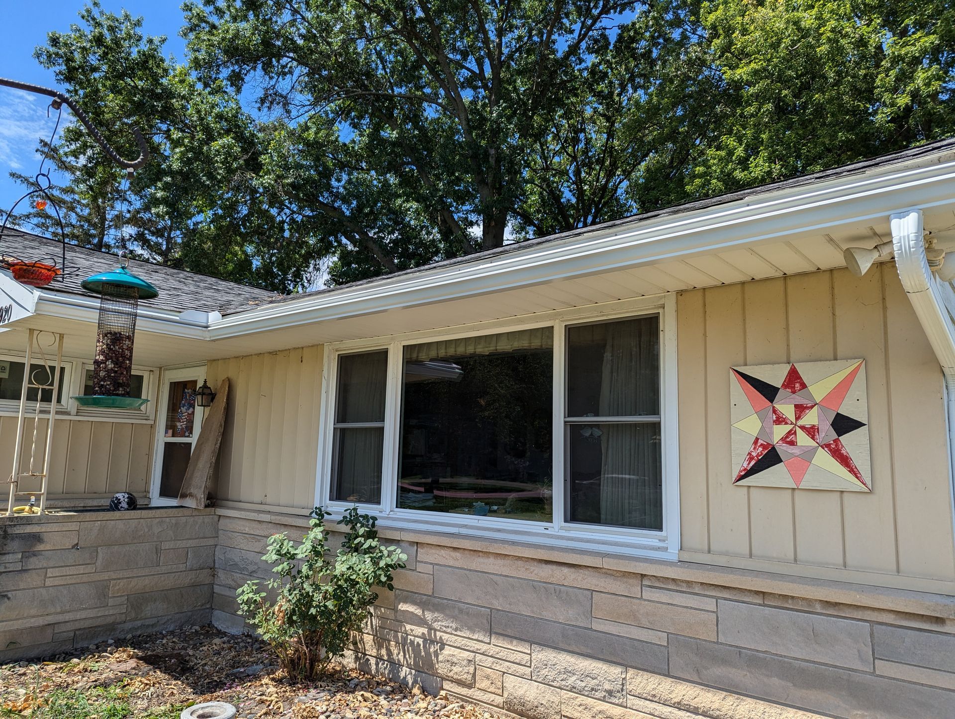 House exterior with tan siding, white trim, and a colorful quilt square.