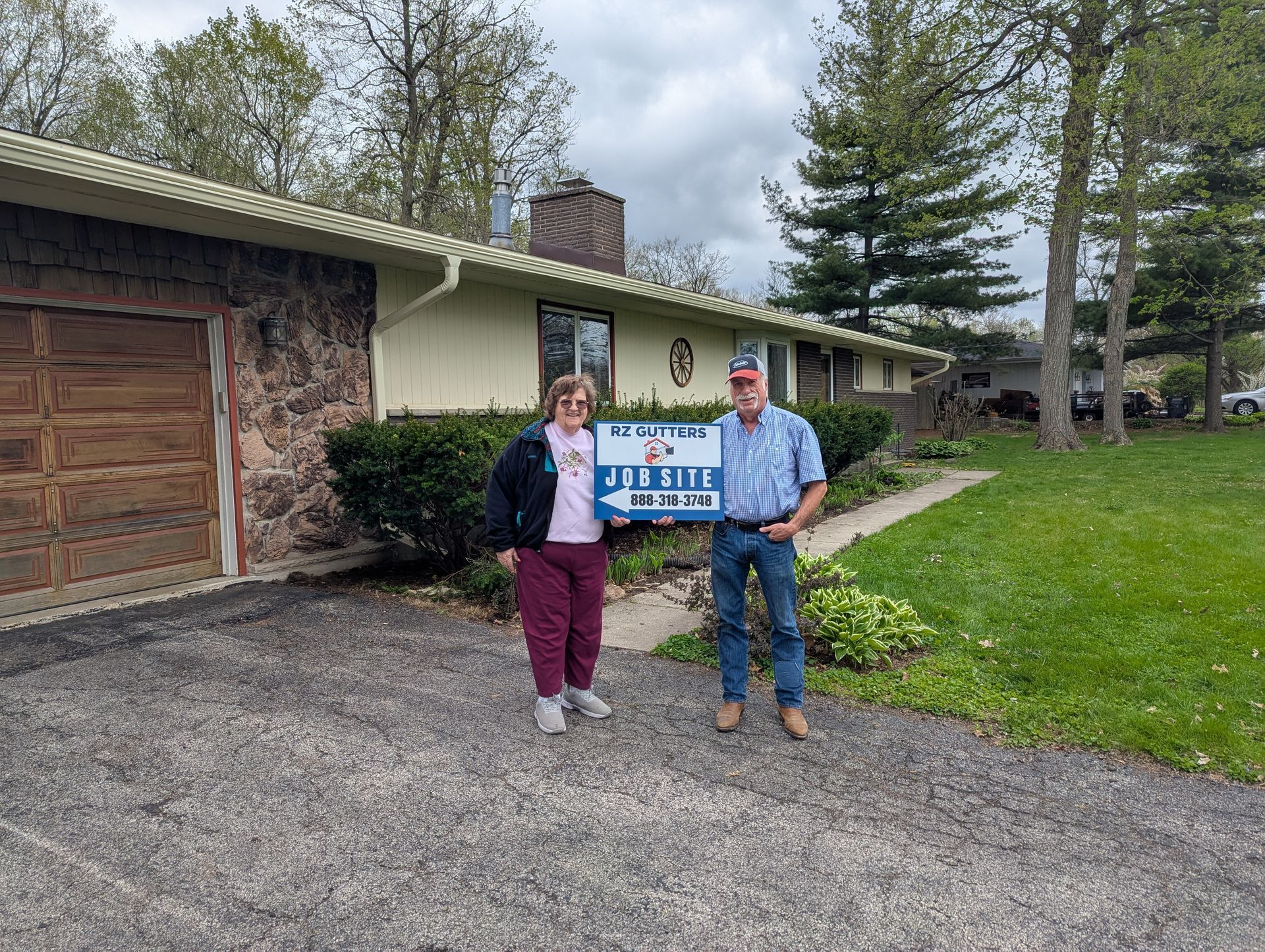 Couple in front of a house holding a sign that says 