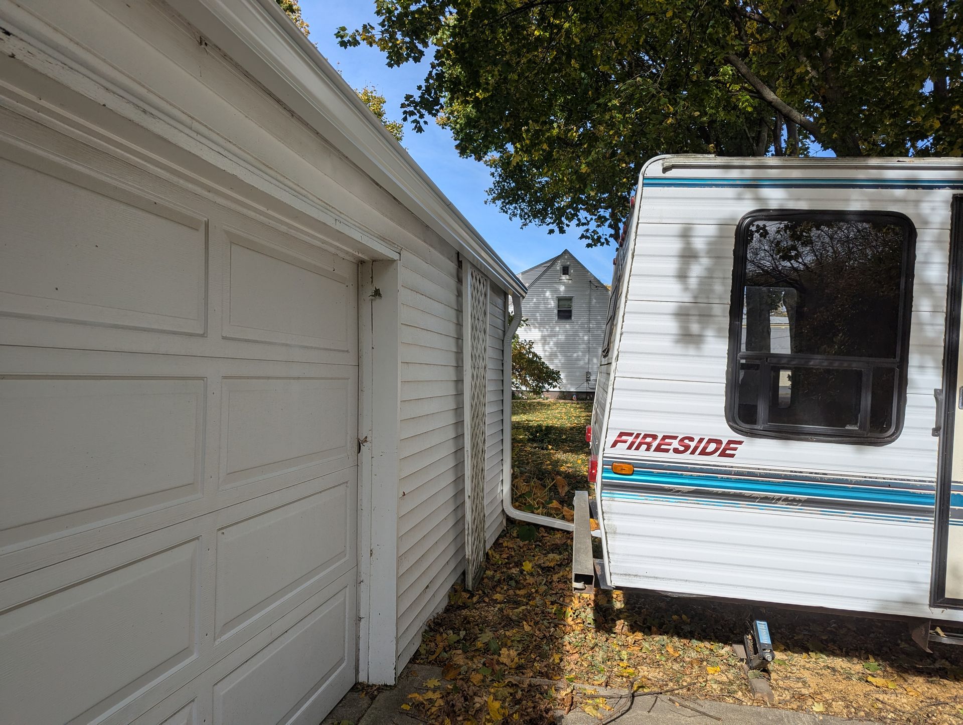 White garage next to a small camper with the word 