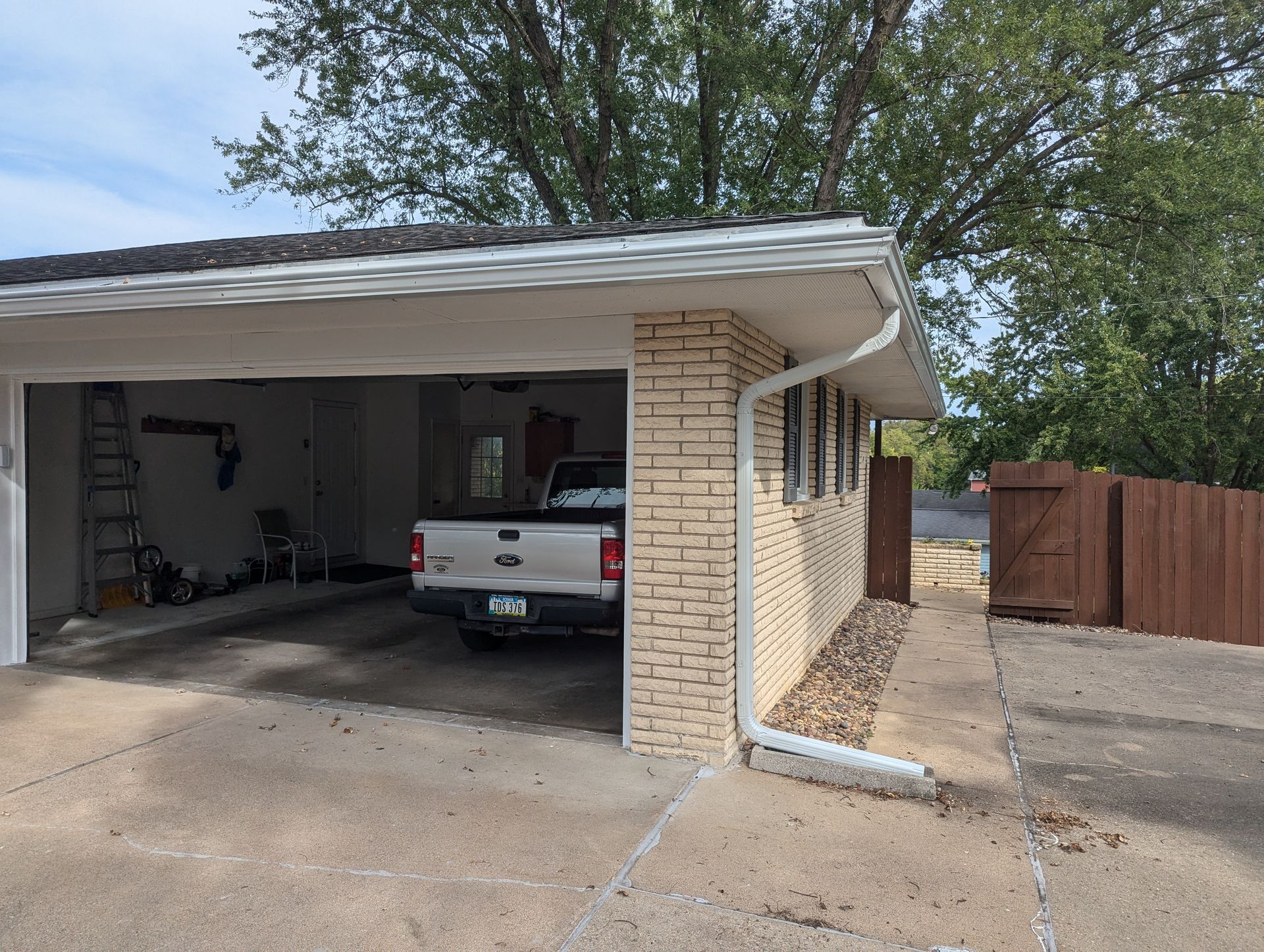 A one-car garage with a pickup truck inside, tan brick exterior, concrete driveway and pathway.