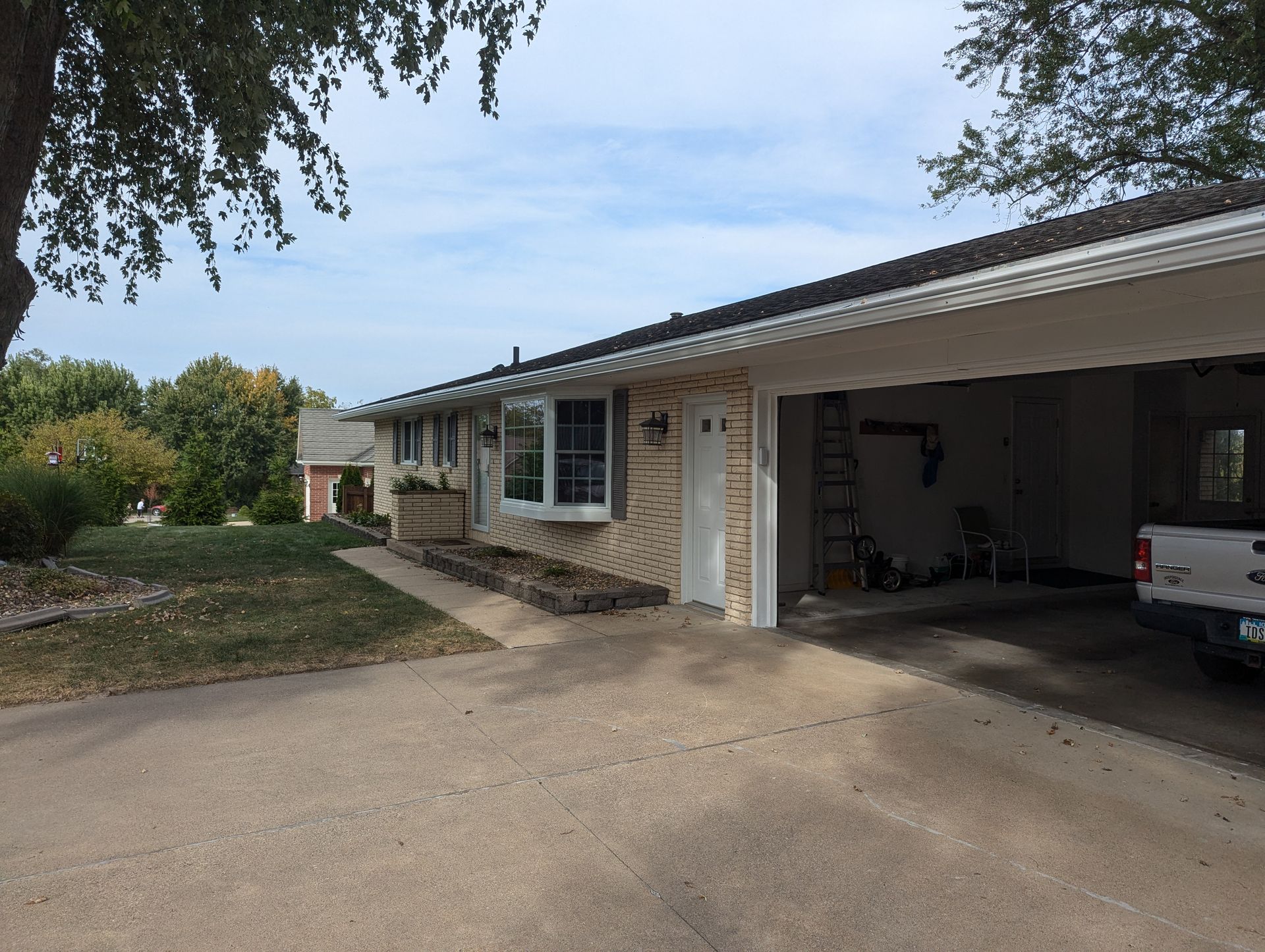 Ranch-style house with attached garage, concrete driveway, and lawn on a cloudy day.