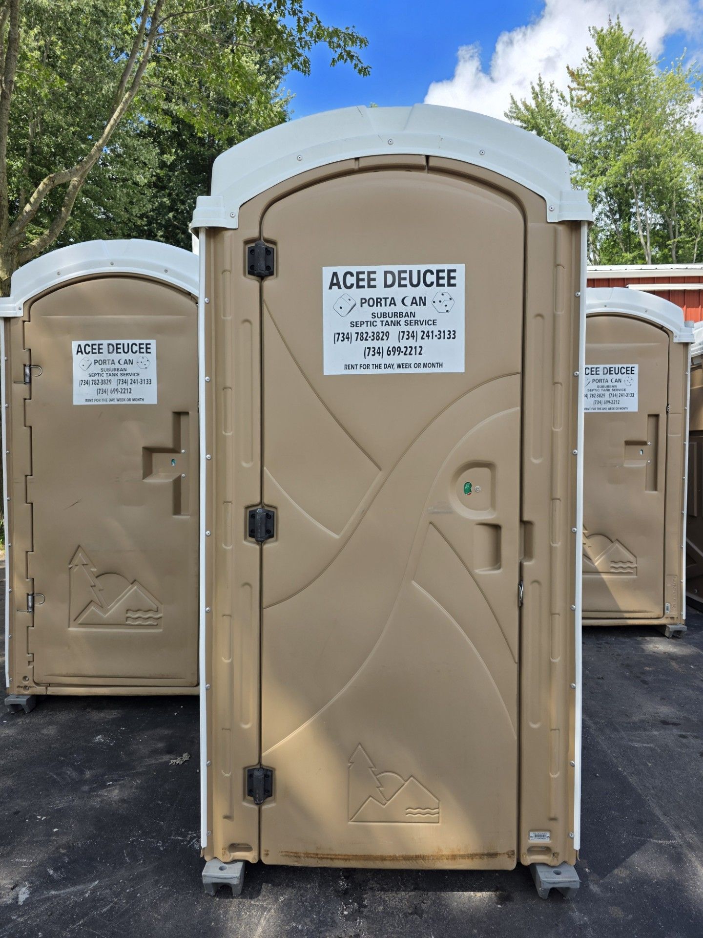 Several tan portable toilets lined up outside.