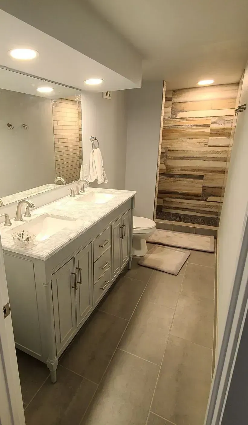 A bathroom with two sinks , a toilet , and a wooden wall.